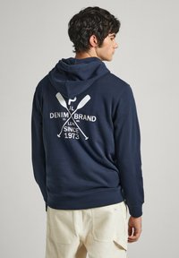 Sudadera azul marino con un bolsillo canguro y capucha con cordón. Presenta un logo impreso en blanco y remos cruzados en la parte posterior. Material de suave mezcla de algodón.