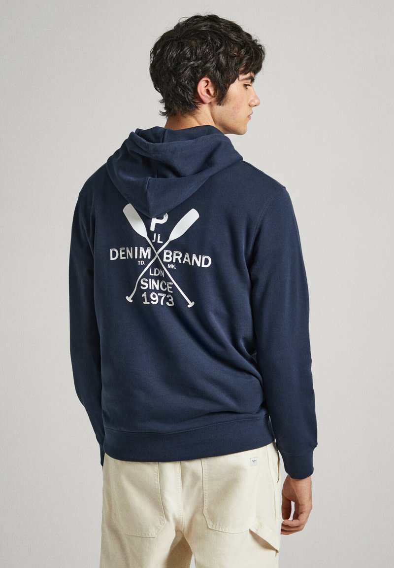 Sudadera azul marino con un bolsillo canguro y capucha con cordón. Presenta un logo impreso en blanco y remos cruzados en la parte posterior. Material de suave mezcla de algodón.