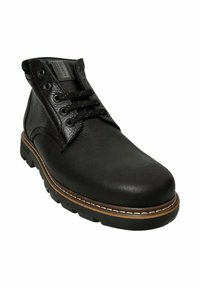 Botas de cuero negro hasta el tobillo con acabado texturizado, puntera redonda, suela marrón, costuras en contraste y ojetes de metal para los cordones.
