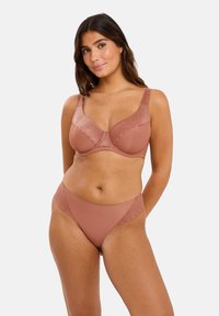 Ensemble de lingerie mauve comprenant un soutien-gorge avec des bonnets en dentelle texturée et des bretelles larges, associé à des culottes taille basse assorties. Finition en tissu doux.