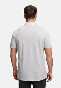 Harmaa lyhythihainen poolopaita, jossa on klassinen kaulus, sileä pinta ja hienovarainen meleerattu kuvio. Ei näkyviä logoja.