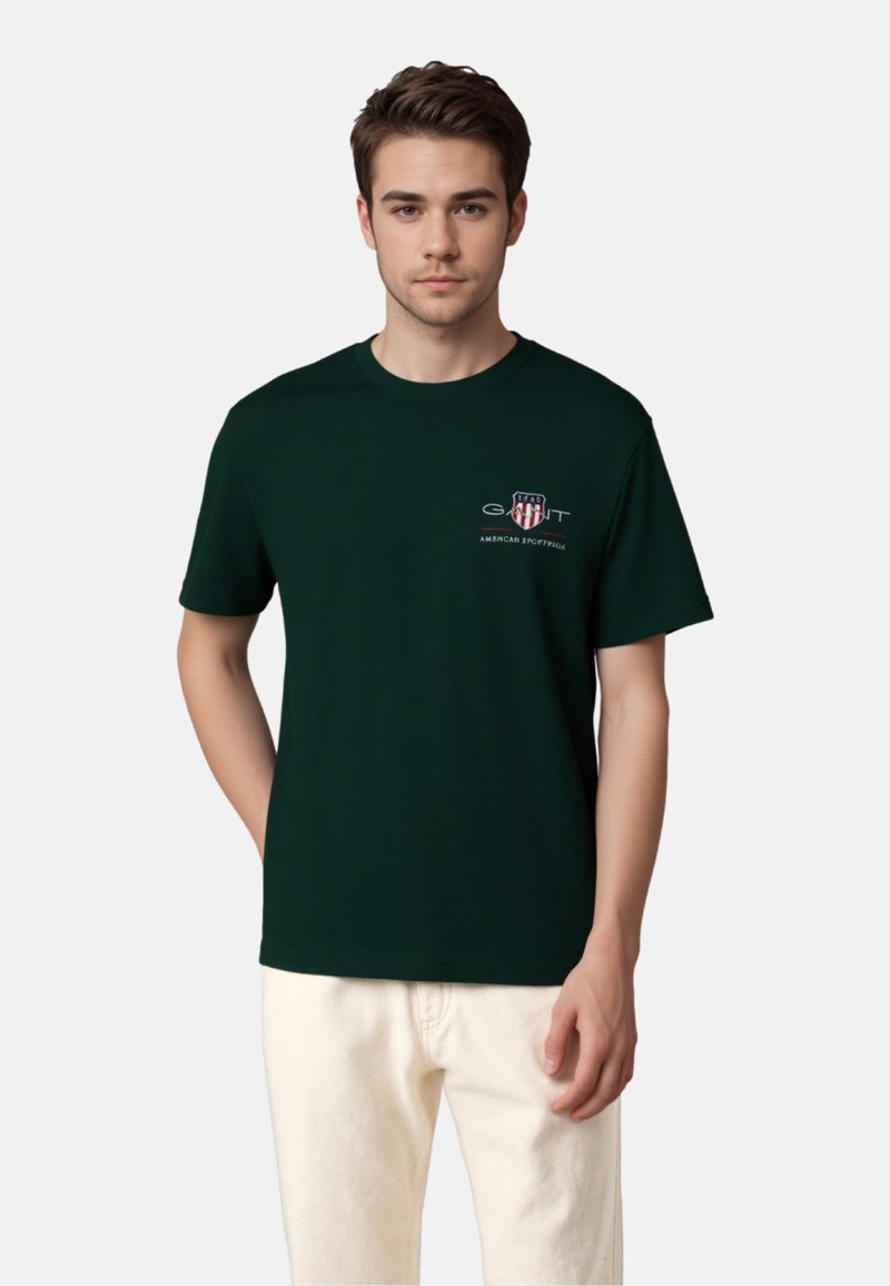 Dark green t-shirt made of cotton, featuring a small logo and text on the left chest area. Short sleeves and a crew neck design.