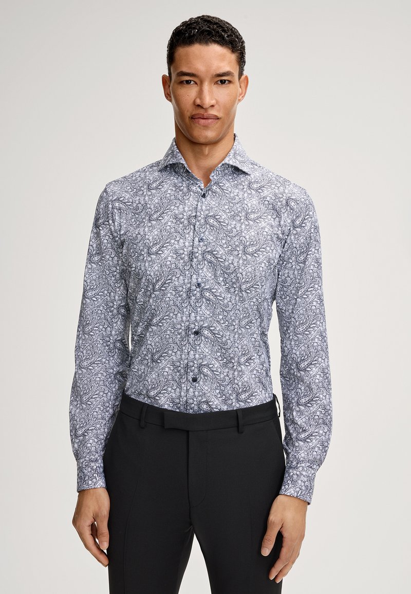 Camicia a maniche lunghe con bottoni in un motivo paisley, caratterizzata da una combinazione di colori bianca e blu navy, con un design aderente e bottoni neri a contrasto.