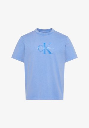 Vaaleansininen lyhythihainen T-paita, jossa on "Calvin Klein"-logo ja suuret "cK"-alkukirjaimet, jotka on painettu tummansinisinä rintaan.