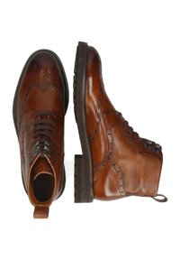 Stivaletti alla caviglia in pelle marrone con dettagli brogue, chiusura con lacci, inserti laterali testurizzati e suola in gomma spessa.