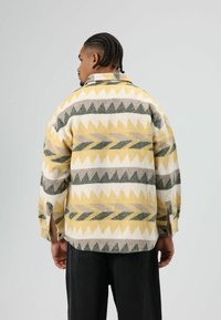 Wollen oversized overhemd met een geometrisch patroon in geel, grijs en crème, met laatvallende schouders en zijsplitten. Met een gestructureerde afwerking.