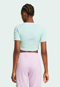 Ljusblå kortärmad t-shirt med rund halsringning. Tillsammans med rosa byxor med elastisk midja, slät textur.