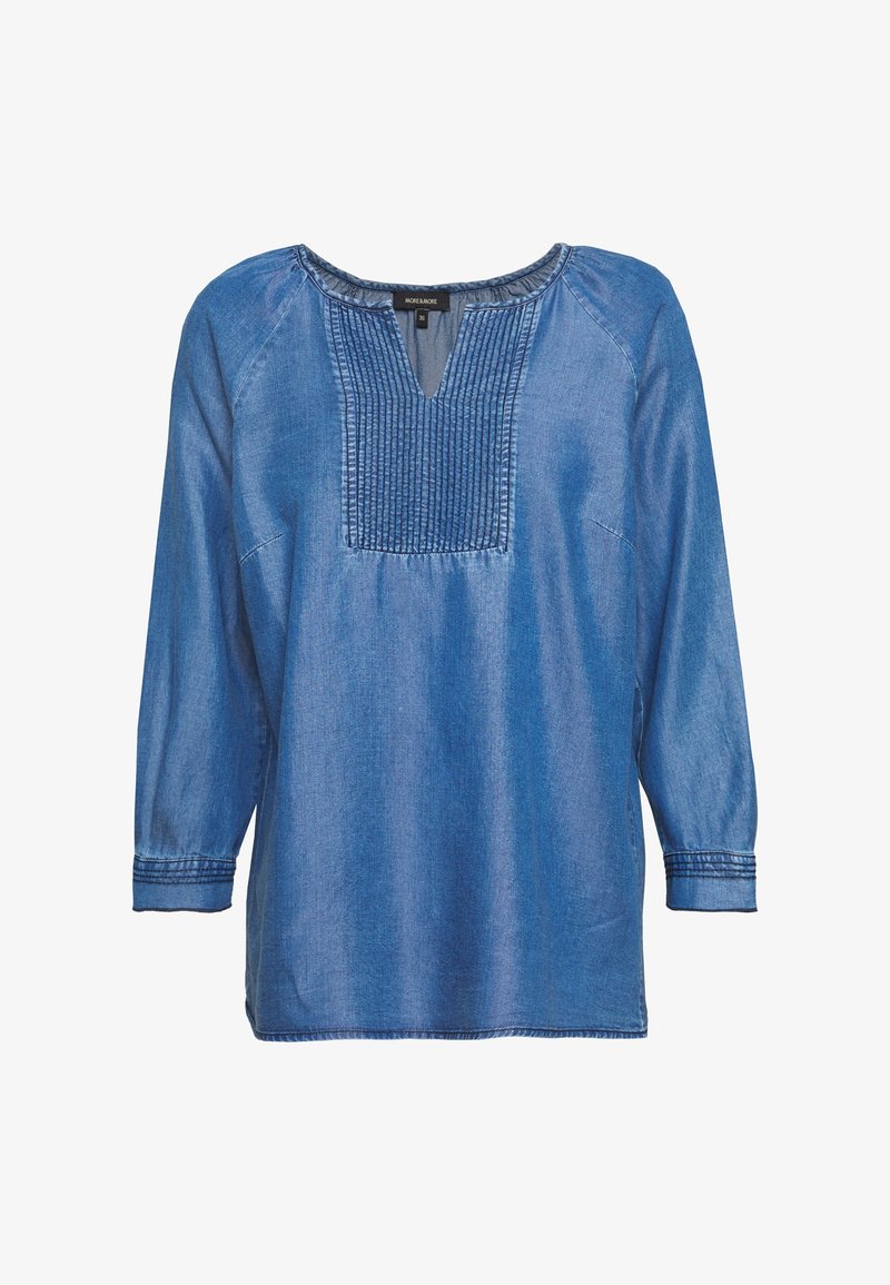 Blouse en denim bleu à manches longues avec des plis cousus sur le plastron avant et une petite ouverture en V.