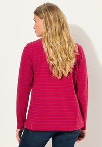 Rotes Langarmshirt mit blauen horizontalen Streifen. Weicher Stoff, lockere Passform, runder Ausschnitt, mit abgerundetem Saum unten.