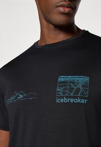 Camiseta negra de manga corta hecha de tela suave, con diseños de montañas azules y líneas de mapa, y el texto "icebreaker" en el frente.