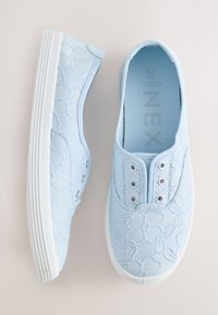 Chaussures en toile bleu clair à enfiler avec broderie florale et semelles blanches en caoutchouc, vues de dessus et de côté.