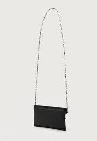 Čierna umelá kožená crossbody taška s tenkým obdĺžnikovým tvarom. Obsahuje reťazový popruh a zips uzatváranie pozdĺž hornej hrany.