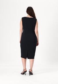 Abito midi senza maniche nero con una silhouette aderente, zip sul retro e spacco posteriore. Tessuto liscio con un design pulito.