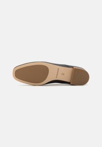 Black leather shoe sole with a smooth finish and a light tan rubber outsole. Notable logo and size information embossed on the heel area.