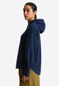 Marineblauer Fleece-Hoodie mit lockerem Schnitt, großer Kapuze und langen Ärmeln. Verfügt über eine Seitentasche und einen abgerundeten Saum für zusätzlichen Komfort.