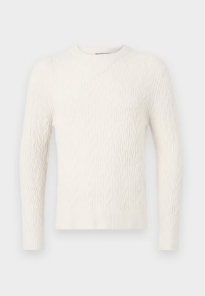 Maglione crema a trecce con maniche lunghe, scollo rotondo e orlo a coste. Presenta un motivo testurizzato su tutta la stoffa.