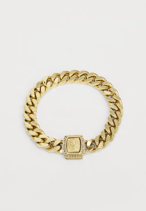 Gold chain bracelet featuring large links, a central emblem with a lion design, and encrusted accents for added detail.