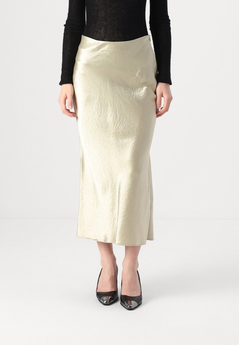 Gonna midi in raso color crema con una texture liscia, spacco laterale e un semplice design in vita, abbinata a décolleté nere in vernice.