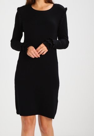Robe noire à manches longues, avec des poignets côtelés ornés de volants, un col rond et une silhouette ajustée. Tissu tricot doux, longueur genoux.