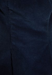 Tamno plavi korduroy materijal s okomitim rebrastim teksturom; uključuje bočni šav s malim prorezom za dodatni dizajn.