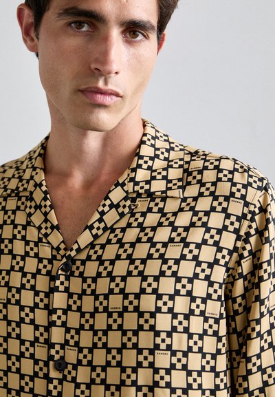 Kortärmad shirt in zwart en beige met een geometrisch patroon van vierkanten en kruisen, met een ingevoegd kraag en knoopsluiting.