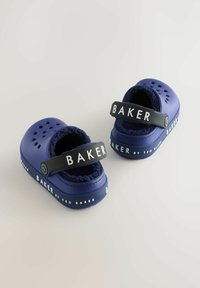 Ljubičaste sintetičke klompe s perforacijama, mekani unutrašnjost i crna traka s oznakom "BAKER." Naglašene bijelim tekstom duž đona.