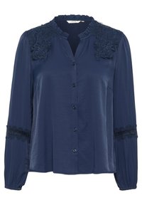 Blouse bleu marine avec des accents floraux brodés sur les épaules, décolleté à volants, fermeture à boutons sur le devant et bordure en dentelle aux manches. Texture douce.