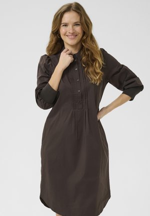 Brown button-up dress with a pleated front, three-quarter sleeves, and contrasting black cuffs. Smooth, lightweight fabric, knee-length design.