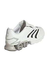 Baltas sporta apavi ar melnajām svītrām, mīksta zole ar cauruļveida atsperveida sekcijām un mīkstināts apkaklīte, redzams no aizmugures sānu skata.