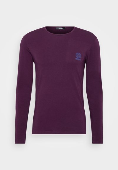 Dlouhý rukáv, fialové bavlněné tričko s kulatým výstřihem a malým modrým logem Versace na levé části hrudi. Měkká struktura a přiléhavý střih.