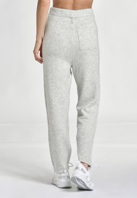 Grå ullbyxor med smal passform, ribbat midjeband och detalj i bakfickan, parat med vita snörskor.