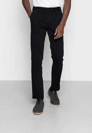 Zwarte chino's van katoen met een recht model. Gecombineerd met donkergrijze schoenen met veters en een lichte zool.