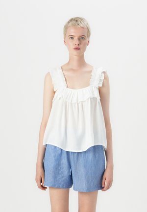 White sleeveless top with ruffled straps and a gathered neckline, paired with blue striped shorts. Smooth fabric, casual design.