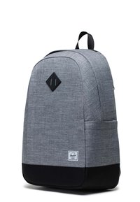 Mochila de tela gris con fondo negro, forma redondeada, acento en forma de diamante en la parte frontal, bolsillo lateral y una etiqueta de marca cerca de la base.