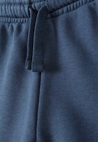 Pantaloni della tuta blu scuro con un cinturino testurizzato e coulisse, realizzati in un tessuto morbido e liscio e con una vestibilità aderente.