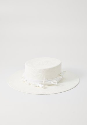 Wide-brimmed white hat made of woven material featuring a flat crown, smooth texture, and a decorative band with bows around the base.