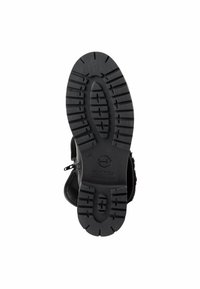 Semelle de bottes noire avec un motif de bande de roulement profond, dotée d'un bout arrondi et d'une fermeture éclaire sur le côté, fabriquée en matériau caoutchouteux texturé pour une meilleure adhérence.