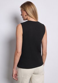 Sort ærmeløs ribbet top lavet af struktureret stof, der viser en tætsiddende silhuet med en buet kant og lodret mønster.