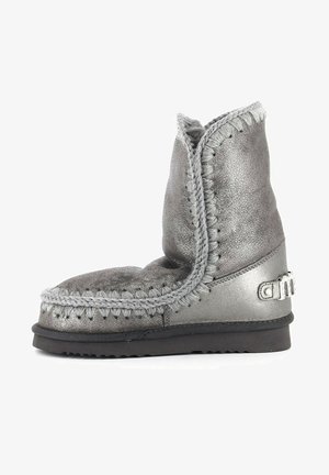 Botín metálico gris con un acabado texturizado, costuras decorativas y un destacado detalle del logo en el lateral. Suela blanda para mayor comodidad.