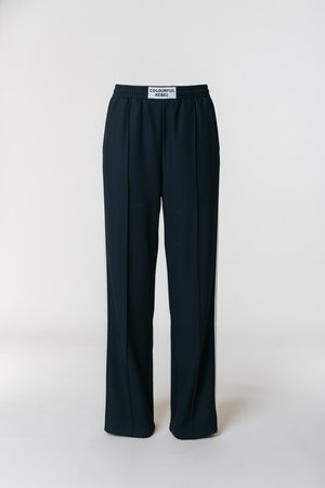 Μαύρο, φαρδύ παντελόνι με ελαστική μέση, κατασκευασμένο από λείο ύφασμα, με ετικέτα "COLOURFUL REBEL" στο πίσω μέρος.