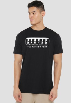 Schwarzes Baumwoll-T-Shirt mit einem Grafikdesign, das das Wort "HUMMER" in Weiß und Grau zeigt, begleitet von dem Text "WIE NIX ANDERES".