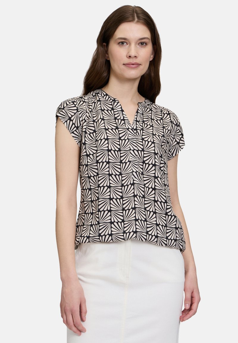 Zwart en crèmekleurig blouse met korte mouwen, voorzien van een geometrisch bladenpatroon, v-hals en een ontspannen pasvorm. Soepele stoftextuur.
