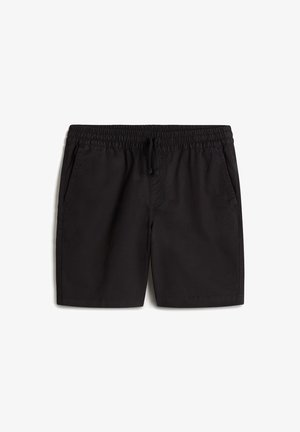 Weißes T-Shirt mit kurzen Ärmeln und schwarzem Logo, kombiniert mit schwarzen Shorts. Das Modell trägt schwarz-weiße Vans-Sneaker mit weißen Socken.