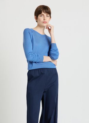 Pull bleu clair à manches longues avec encolure ronde, associé à un pantalon ample bleu marine. Texture lisse, coupe décontractée, détails minimaux.