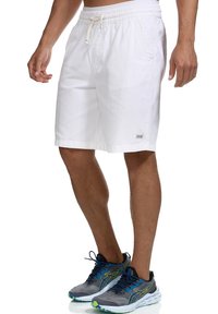 Pantalones cortos de lino blanco con cintura elástica y cordón. Presenta bolsillos laterales y una pequeña etiqueta de la marca en la pierna.