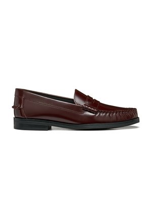 Mocassin en cuir marron foncé avec un petit talon noir et des coutures style mocassin à l'avant et sur les côtés sur fond blanc.