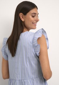 Modra in bela črtasta obleka s kratkimi naborki, prilegajočim bodijem in razširjenim krilom. Gladek bombažni material, lahka tekstura.