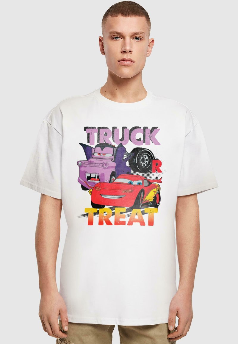 Vit bomullsgrafik t-shirt med en färgglad tryckt design av tecknade bilar, med texten "TRUCK OR TREAT" i fet, lekfull stil. Korta ärmar.