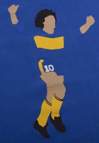 Grafiek van een speler in een blauw shirt met gele accenten, die zwarte schoenen en gele sokken draagt, met het nummer 10.