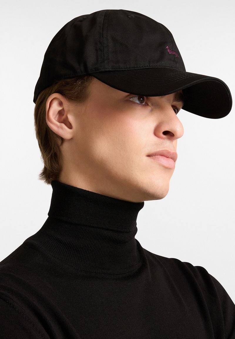 Gorra de béisbol negra con visera curvada, que presenta un pequeño diseño bordado en púrpura. La gorra está hecha de una tela suave.
